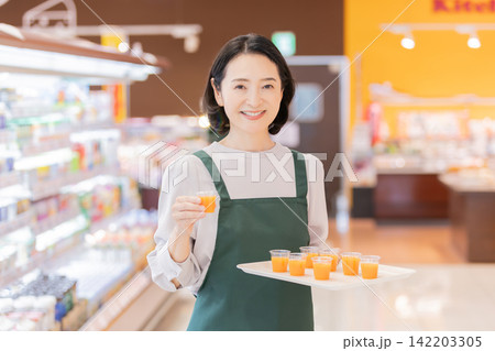 スーパーマーケットで試飲用ドリンクを提供する女性スタッフ スーパーマーケットで試飲用ドリンクを提供する女性スタッフ 142203305