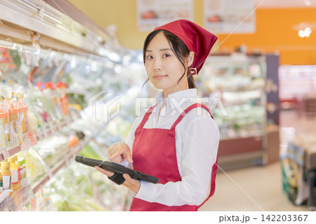 スーパーの野菜売り場でタブレットを操作する女性スタッフ スーパーの野菜売り場でタブレットを操作する女性スタッフ 142203367