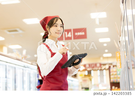 スーパーの冷蔵売り場でタブレットを使い商品管理をする女性店員 スーパーの冷蔵売り場でタブレットを使い商品管理をする女性店員 142203385
