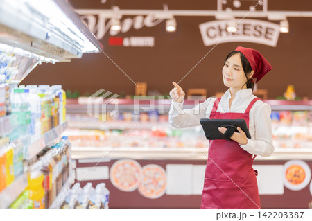 スーパーの飲料売り場で商品を確認するタブレットを持った女性店員 スーパーの飲料売り場で商品を確認するタブレットを持った女性店員 142203387