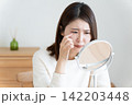 目のトラブルで鏡を見る女性 142203448
