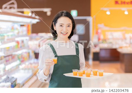 スーパーマーケットで試飲用ドリンクを提供する女性スタッフ 142203476