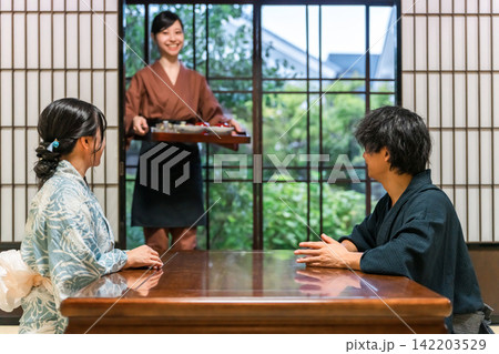 旅館,割烹日本料理店で食事を配膳する旅館スタッフの女性,仲居,女将 旅館,割烹日本料理店で食事を配膳する旅館スタッフの女性,仲居,女将 142203529
