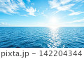太陽光とライトブルーの空と海、雲の少ない快晴の空 142204344