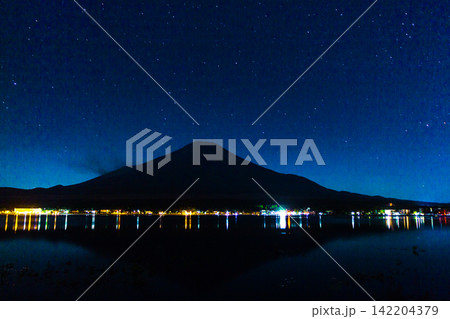 Mount Fuji Beneath an Expansive Starry Sky With Vibrant Lakeside Lights 142204379