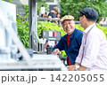 Senior LGBTQ man beams with joy while chatting over coffee at modern outdoor cafe 142205055