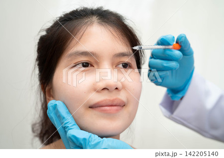 Asian woman receiving plastic surgery shape of nose performed on face. Asian woman receiving plastic surgery shape of nose performed on face. 142205140