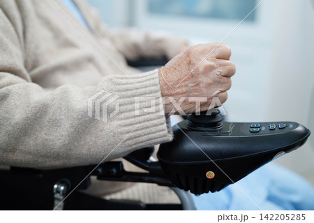 Asian elderly disability woman patient use joystick electric wheelchair in hospital. 142205285