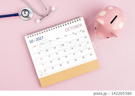 October 2027 desk calendar and stethoscope with piggy bank, Savings for Health insurance concept. October 2027 desk calendar and stethoscope with piggy bank, Savings for Health insurance concept. 142205380