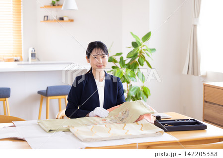 出張買取　訪問先で着物の鑑定をしている鑑定士　 142205388