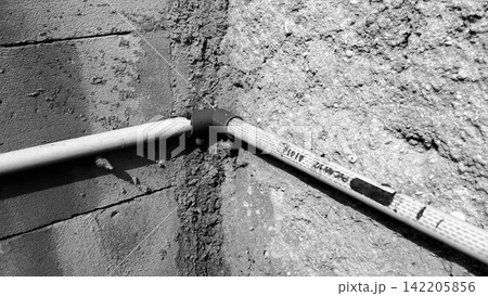 PVC pipe elbow fitting installed on a rough concrete wall. PVC pipe elbow fitting installed on a rough concrete wall. 142205856