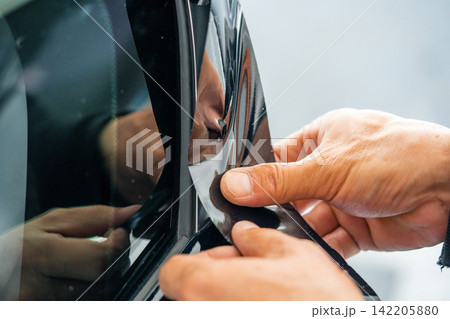 A car wrapping specialist applies a polyurethane film to the car. Detailer PPF 142205880