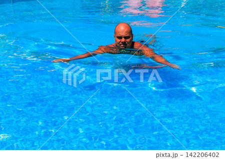 Handsome man relaxing in the swimming pool Handsome man relaxing in the swimming pool 142206402