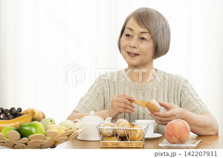 リビングで朝食のパンを食べるシニア女性 142207931