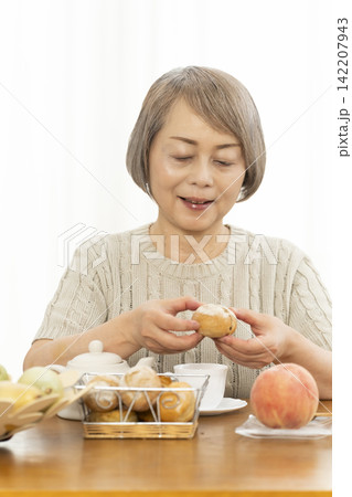 リビングで朝食のパンを食べるシニア女性 リビングで朝食のパンを食べるシニア女性 142207943