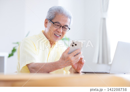 リビングでスマホを見ているシニア男性 142208738