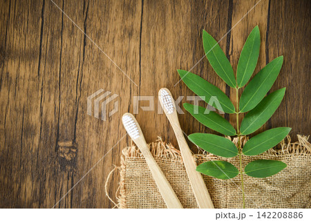 bamboo toothbrush and green leaf on rustic background - Zero waste Bathroom use less plastic concept 142208886