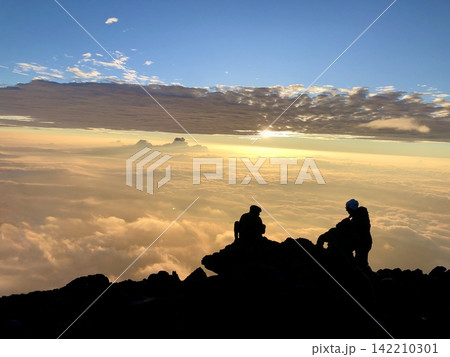 山頂から雲海と朝日を眺める登山者のシルエット 山頂から雲海と朝日を眺める登山者のシルエット 142210301