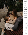 Mom and daughter share a moment on a bench in the park during a sunny day 142210446