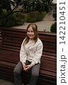 Little girl sitting on a bench in a garden enjoying the sunny day 142210451