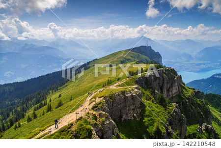 Alpine Mountain Trail with Hikers, Lake View and Dramatic Sky Alpine Mountain Trail with Hikers, Lake View and Dramatic Sky 142210548