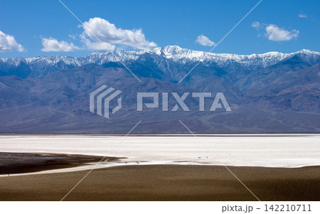 Snowy Mountain Range Over Desert Salt Flat Landscape 142210711