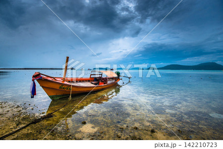 Longtail Boat on Tropical Shore Under Stormy Sky Longtail Boat on Tropical Shore Under Stormy Sky 142210723