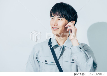 スマホを操作する作業服の男性 スマホを操作する作業服の男性 142212012