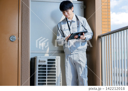 エアコンの室外機を点検する若い男性作業員 エアコンの室外機を点検する若い男性作業員 142212018