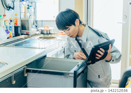 キッチンの食洗機・食器洗い乾燥機を診断・チェック・査定する作業服姿の男性ビジネスマン キッチンの食洗機・食器洗い乾燥機を診断・チェック・査定する作業服姿の男性ビジネスマン 142212036
