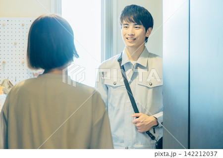 顧客の家に上がる作業服姿の男性業者と出迎える主婦 顧客の家に上がる作業服姿の男性業者と出迎える主婦 142212037