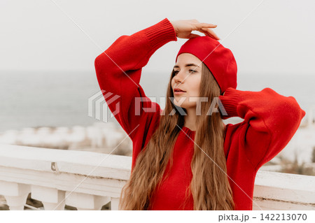 Woman beret sweater poses on a white balcony overlooking the sea during autumn for a stylish lifestyle fashion portrait Woman beret sweater poses on a white balcony overlooking the sea during autumn for a stylish lifestyle fashion portrait 142213070