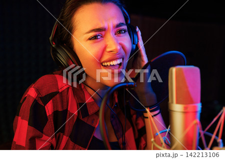 Close-up of young woman singing emotionally in a recording booth 142213106