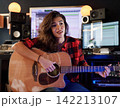 Woman with guitar rehearses song in studio 142213107