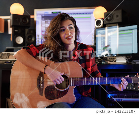 Woman with guitar rehearses song in studio 142213107