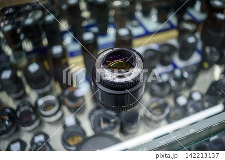 Camera lens at the center of a photography store display surrounded by out-of-focus lenses in a grid pattern Camera lens at the center of a photography store display surrounded by out-of-focus lenses in a grid pattern 142213137