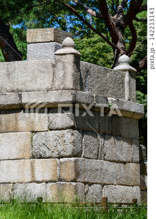 A weathered stone structure set against lush greenery, featuring intricate vertical walls A weathered stone structure set against lush greenery, featuring intricate vertical walls 142213143