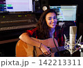 Portrait of a smiling woman guitarist in recording studio looking at camera 142213311