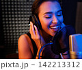 Young smiling female singer performing in a studio under colorful lights 142213312