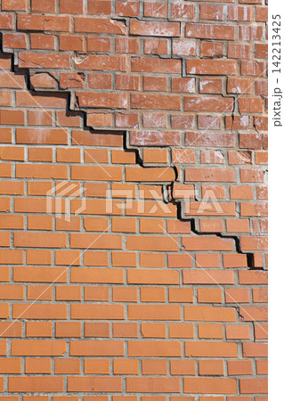 A large crack runs diagonally across a brick wall. A large crack runs diagonally across a brick wall. 142213425