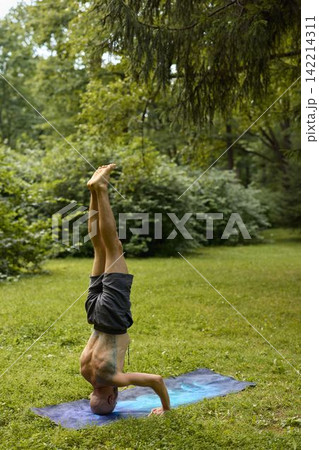 Caucasian man meditative headstand, wellness practitioner 142214311