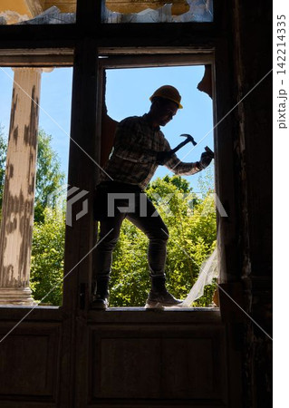 Mechanic in safety gear performing precise window repair task 142214335