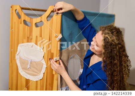 Caucasian woman inspecting fabric stitching on organizer Caucasian woman inspecting fabric stitching on organizer 142214339