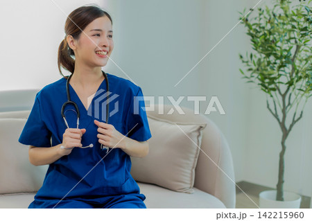 Beautiful Doctor wearing hospital uniform seat at sofa - Cheerful Asian female working at the hospital Beautiful Doctor wearing hospital uniform seat at sofa - Cheerful Asian female working at the hospital 142215960