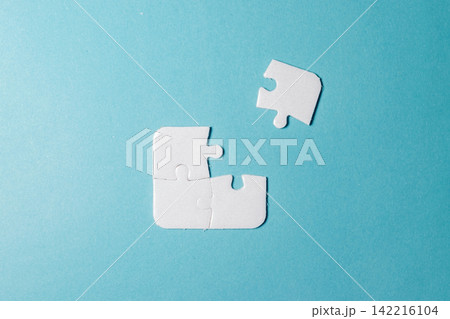 Three connected white jigsaw puzzle pieces with one separate piece remaining to be fitted on blue. High Quality Photo Three connected white jigsaw puzzle pieces with one separate piece remaining to be fitted on blue. High Quality Photo 142216104