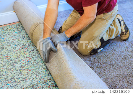 Handyman works on laying down new carpet in home room Handyman works on laying down new carpet in home room 142216109