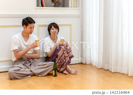 床に座ってワインを楽しむ若いカップル 床に座ってワインを楽しむ若いカップル 142216964