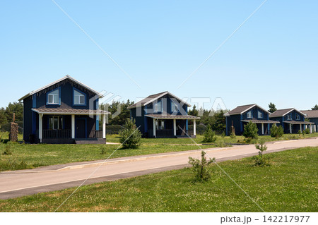 Modern vacation cottages located along the road amid lush summer scenery. Modern vacation cottages located along the road amid lush summer scenery. 142217977