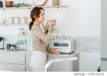 キッチンで手軽にグラノーラで朝食を取るアジア人女性 キッチンで手軽にグラノーラで朝食を取るアジア人女性 142218232