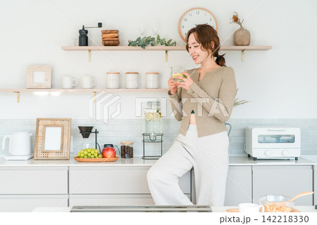 キッチンカウンターでデトックスウォーターを飲む女性 キッチンカウンターでデトックスウォーターを飲む女性 142218330
